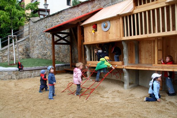 Kinder klettern das neue Holzgeländer des Spielplatzes hoch