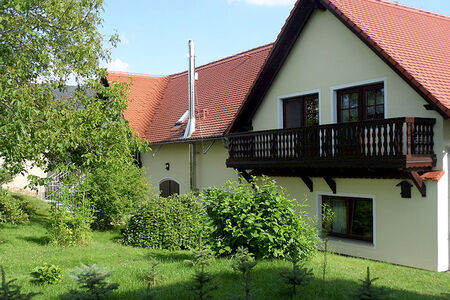 Garten mit Wiese, Bäumen und Sträuchern und gelbes Haus mit rotem Spitzdach