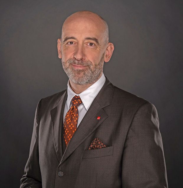 Mann in grauem Anzug mit weißem Hemd und brauner Krawatte