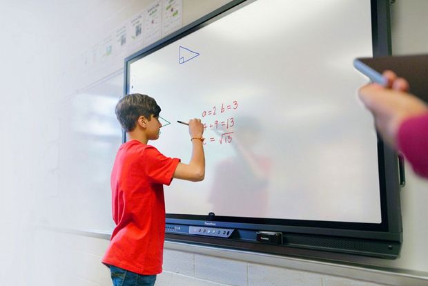 Ein Schüler schreibt an einer interaktiven Tafel