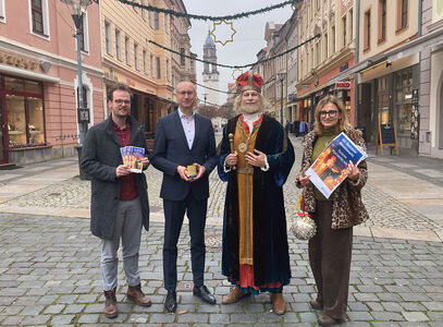 Bautzen freut sich auf den 641. Wenzelsmarkt vier Personen halten Faltblätter, Plakat und Glühweintasse vom Wenzelsmarkt in der Hand