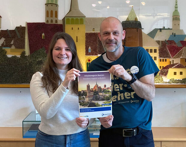 Urlaubsmagazin 2025 Junge Frau hält gemeinsam mit einem Mann eine Broschüre in der Hand