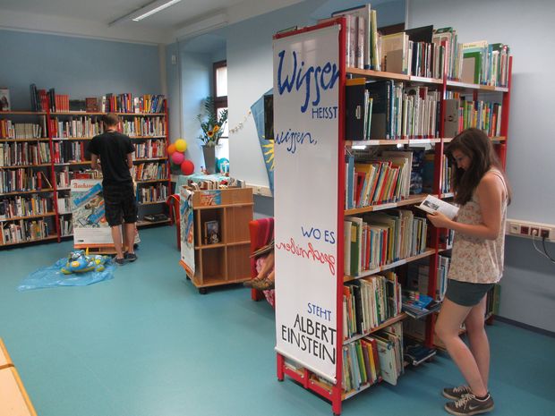 Jugendliche stöbern in Bücherregalen