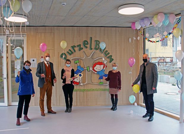 Personen stehen vor einer Wand in einen mit Ballons geschmückten Raum