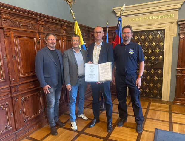 Kooperationsvereinbarung Stadtverwaltung und AOK die vier Beteiligten stehen im Rathaus und halten sie Kooperationsvereinbarung
