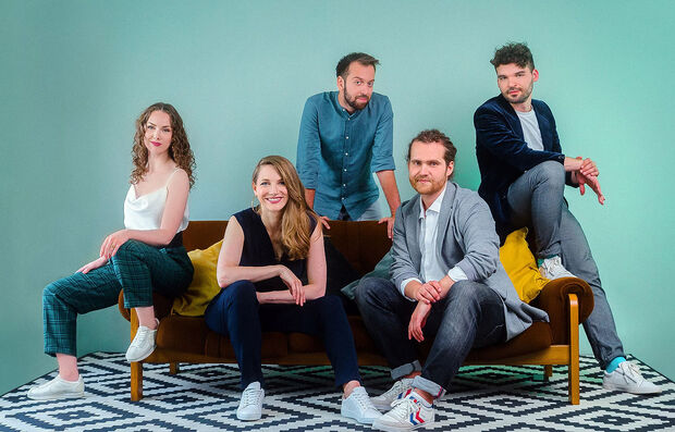 Quintense Zwei Frauen und drei Männer sitzen auf einem geloben Foto