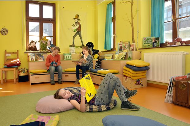 Kinder-und Jugendbibliothek Drei Kinder sitzen im Zimmer verteilt und lesen Bücher