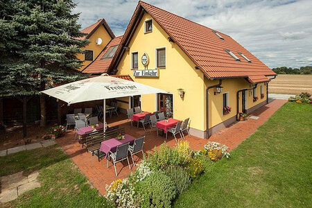 gelbes Haus mit rotem Spitzdach, davor Biergarten