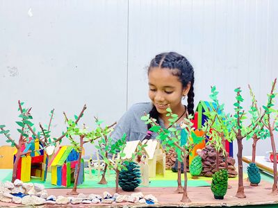 Ausstellung SPREJNIK Ein Kind sitzt vor einem gebastelten Landschaftsbild