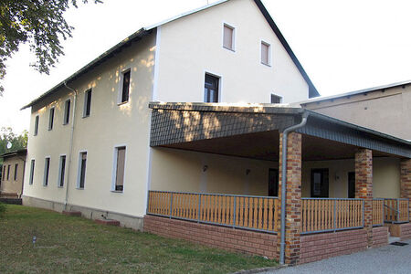 großes weißes Haus mit Spitzdach und überdachter Terrasse