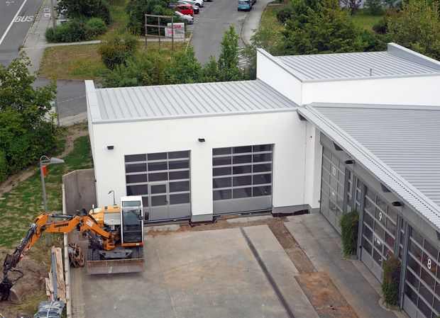 Anbau Feuerwache weiße Gebäude im Vordergrund ein kleiner Bagger