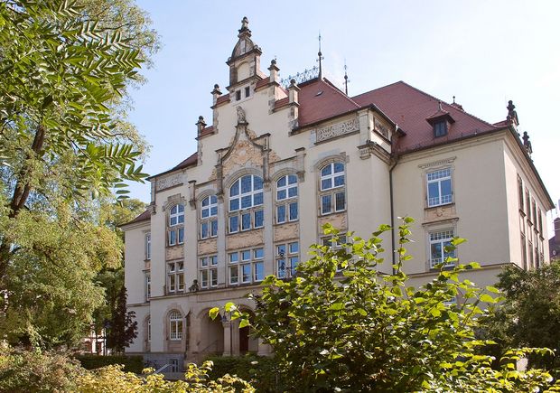 Schiller Gymnasium- helles Gebäude mit vielen barocken Verziehrungen, im Vordergrunf- Bäume