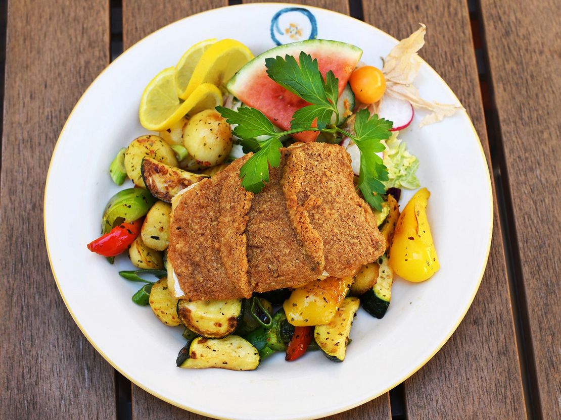 Teller angerichtet mit paniertem Fleisch und und buntem Grillgemüse