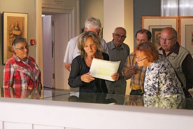 Ein Foto einer Führung durch das Museum Bautzen. Eine Gruppe von sechs Menschen steht an einer Vitrine und eine Frau erklärt etwas zum Inhalt der Vitrine.