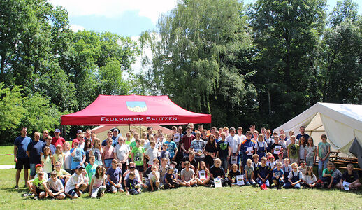 Mädchen und Jungen sitzen auf Wiese im Spreebad
