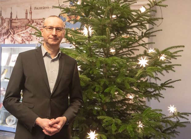 Oberbürgermeister Karsten Vogt steht vor einem Weihnachtsbaum