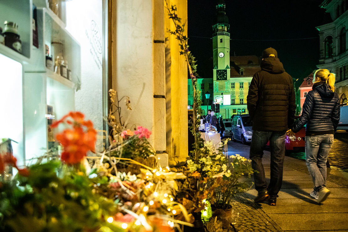 Einkaufsnacht Romantica Junges Paar läuft Hand in Hand im abendlichen Bautzen auf das auf das Rathaus zu (gelb). Im Vordergrund ein dekoriertes Schaufenster.