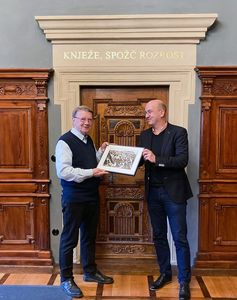 Auszeichnung Wuschansky Mann überreicht einem zweiten Mann ein Geschenk