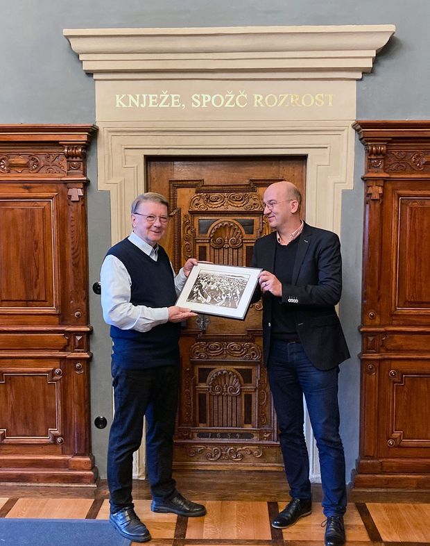 Auszeichnung Wuschansky Mann überreicht einem zweiten Mann ein Geschenk