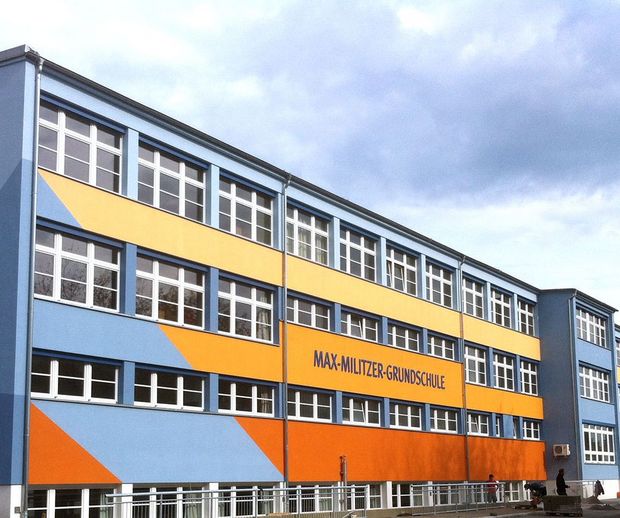 Max-Militzer-Grundschule Militzer Grundschule- Schrägansicht des blau en Gebäudes, mit gelben, orangenen und roten schrägen Streifen
