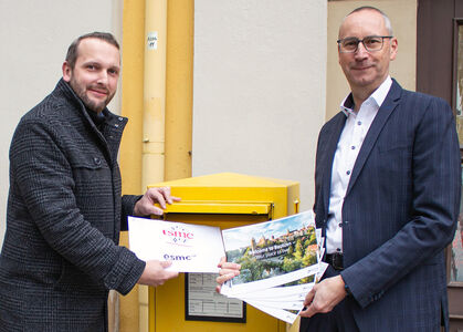 OB Vogt und Baubürgermeister Nowak Zwei Männer stehen vor einem gelben Briefkasten und werfen Post ein.