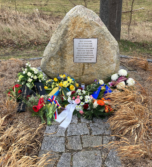 Gedenkstein Groß Rosen Gedenkstein mit Inschrift, davor liegen Blumengebinde