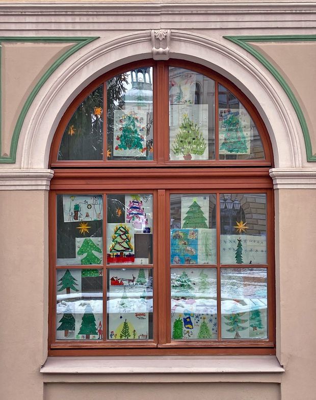 Bilder von gemalten Weihnachtsbäumen hängen in einem Fenster