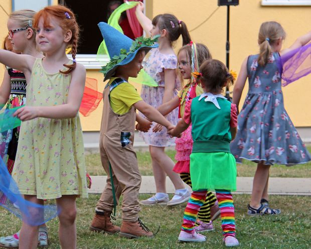 Kinder tanzen in bunten Kostümen zusammen