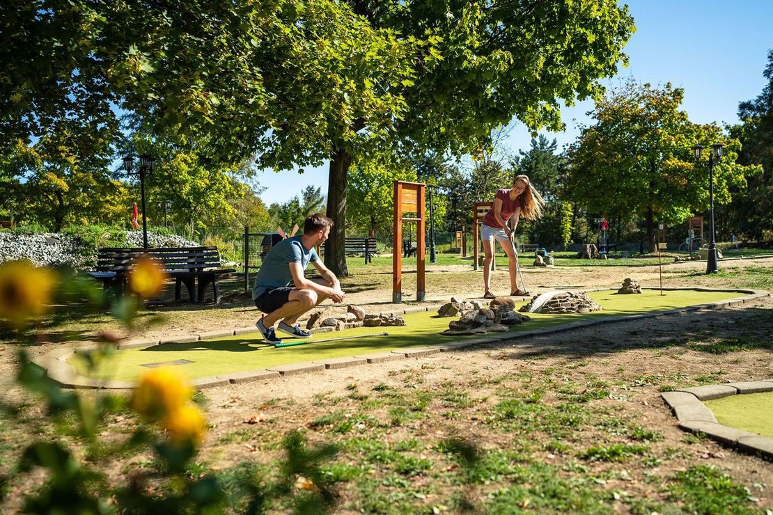 Mitte: zwei Personenn spielen Minigolf