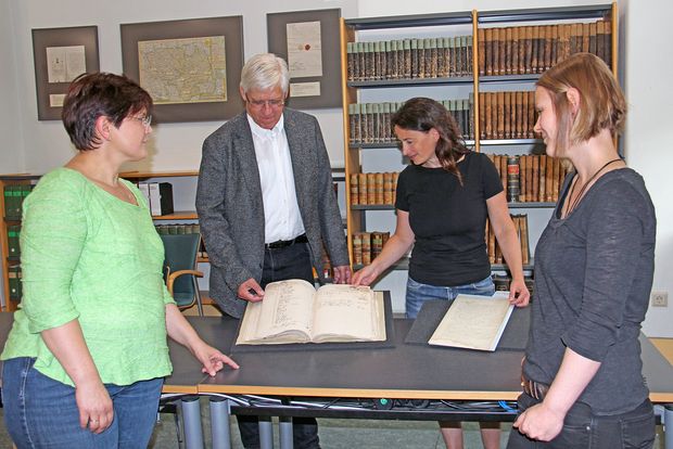 Übergabe restaurierte Akte an Archivverbund drei Frauen und ein Mann stehen um ein altes Buch