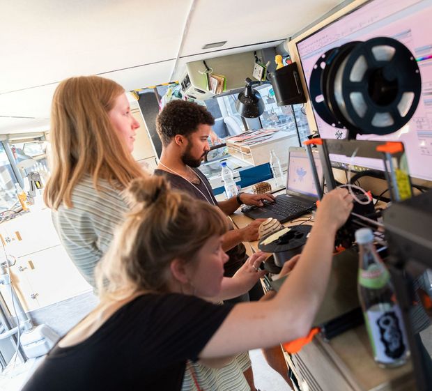 Fabmobil Drei Schüler, zwei Mädchen und ein Junge, tüfteln an Geräten