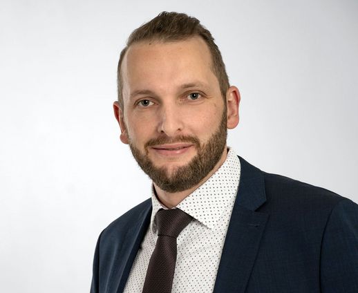 Mann im weiß-gepunktetem Hemd mit Krawatte und blauem Jacket