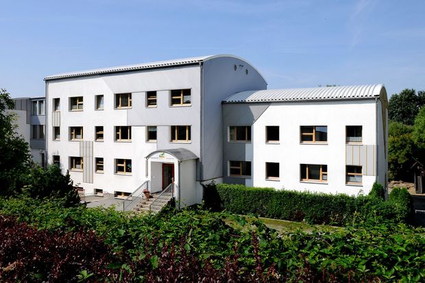 Kita Findikus- modernes weißes Gebäude, im Vordergrund- eine grüne Hecke als Abgrenzung