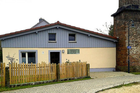 gelbes Haus mit Spitzdach, oben graue Holzverkleidung