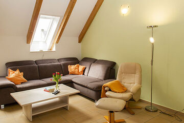 Weichaer Hof unterm Dach: braune Eckcouch mit Couchtisch und beigefarbenem Ledersessel mit Hocker