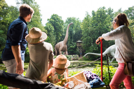Familie im Saurierpark Vordergrund Familie, Hintergrund zwei Dinosaurier