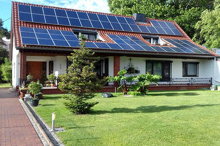 weißes Haus mit rotem Spitzdach und Solaranlage