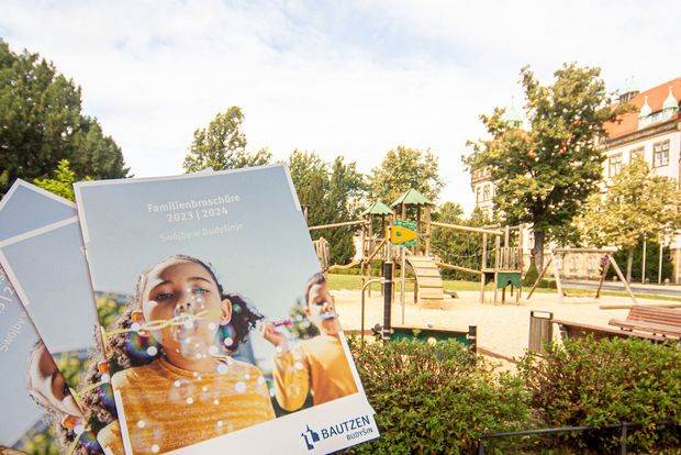 Familienbroschüre 2023 | 2024, im Hintergrund Spielplatz