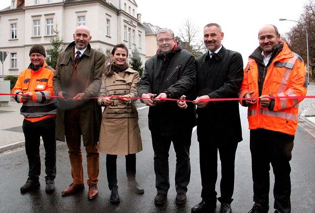 Eine Frau und fünf Männer zerschneiden ein rotes Band, dass über die Straße gespannt ist