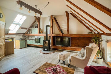 Ferienwohnung „Am Kirschbaum“ Wohn-/Essbereich unterm Dach, sichtbare Balken, Couch und Sessel, Kamin