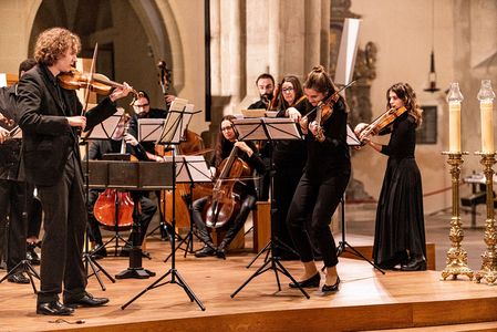 Orchester bestehend aus Frauen und Männer spielen auf Instrumenten