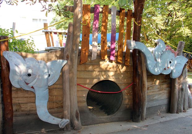 Kinderspielplatztunnel geschmückt mit Elefantenköpfen aus Holz