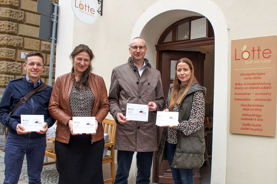 Zwei Frauen und zwei Männer halten je ein Schild und stehen vor dem Geschäft Lotte