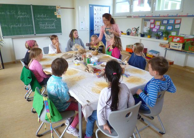 Kinder sitzen im Klassenzimmer, an einem Tisch und backen Plätzchen