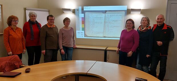 © Archivverbund Abgebildete Personen v.l.n.r.: Frau Nagel, Frau Pohle, Herr Fiebiger, Frau Fiebiger, Frau Ahland, Frau Matthes, Herr Matthes In der Mitte des Bildes die handschriftliche Schülerliste von 1642 bis 1833.